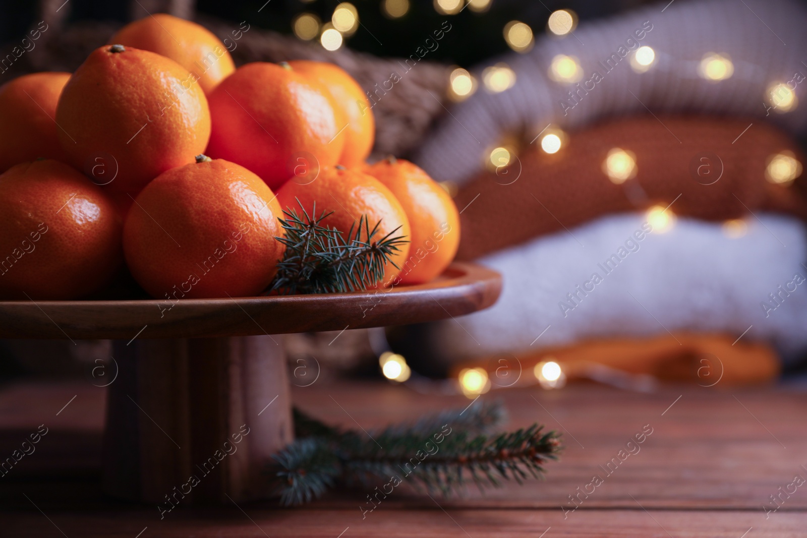 Photo of Stand with delicious ripe tangerines and fir twigs on wooden table. Space for text