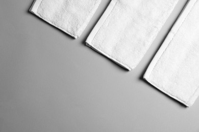 Photo of Soft folded white towels on light grey background, flat lay. Space for text