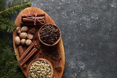 Different spices and fir branches on dark gray table, flat lay. Space for text