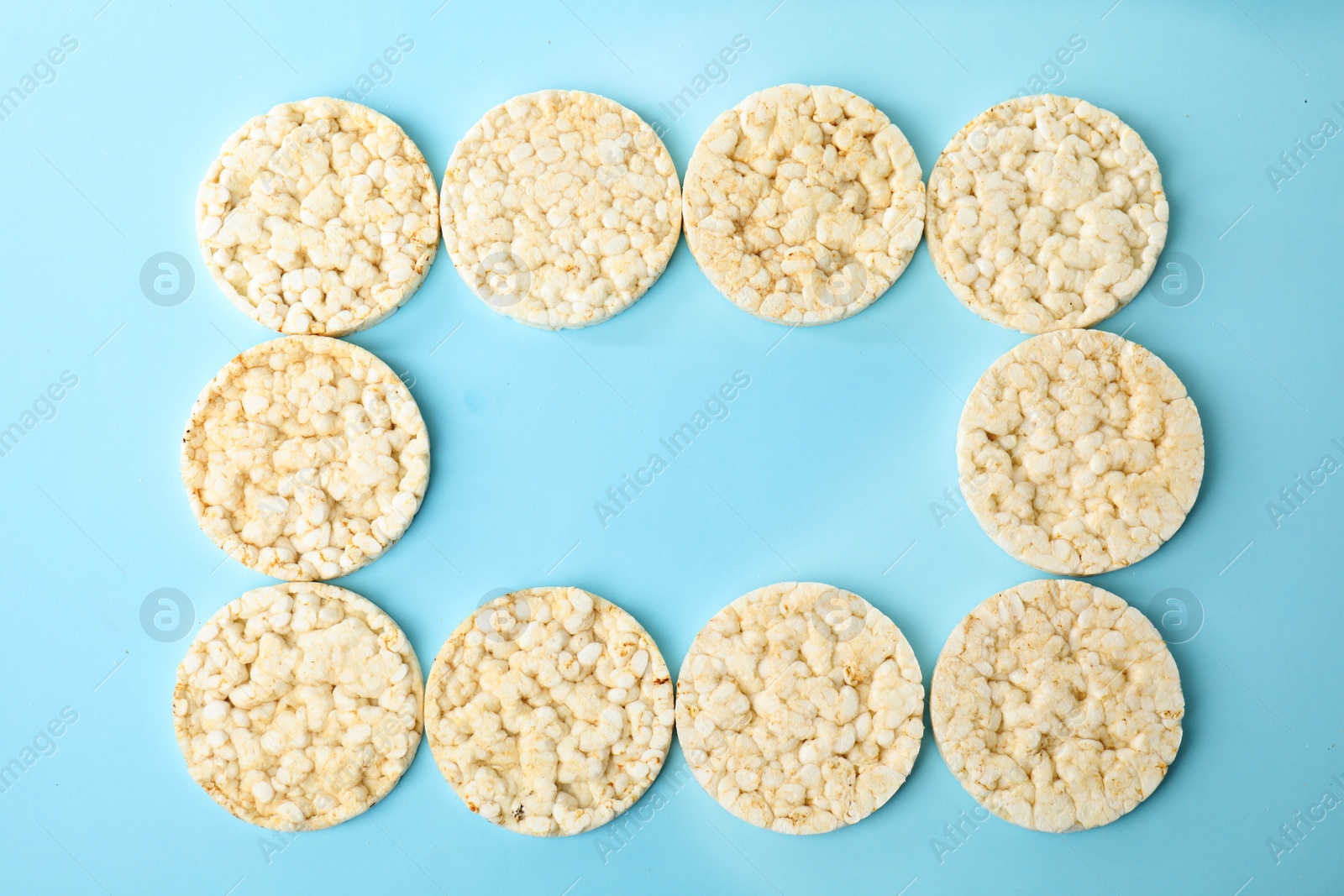 Photo of Frame made of puffed rice cakes on light blue background, flat lay. Space for text