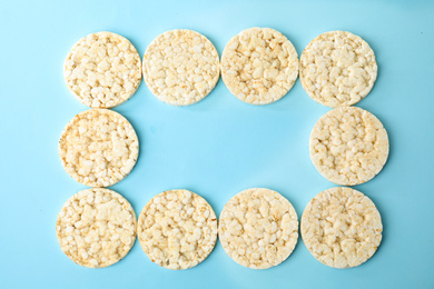 Photo of Frame made of puffed rice cakes on light blue background, flat lay. Space for text