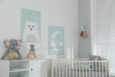 Stylish baby room interior with crib and cute wall art