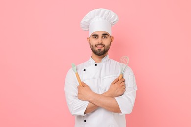 Photo of Professional chef holding kitchen utensils on pink background