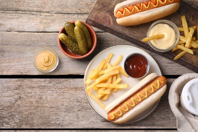 Photo of Flat lay composition with delicious hot dogs and French fries on wooden table. Space for text