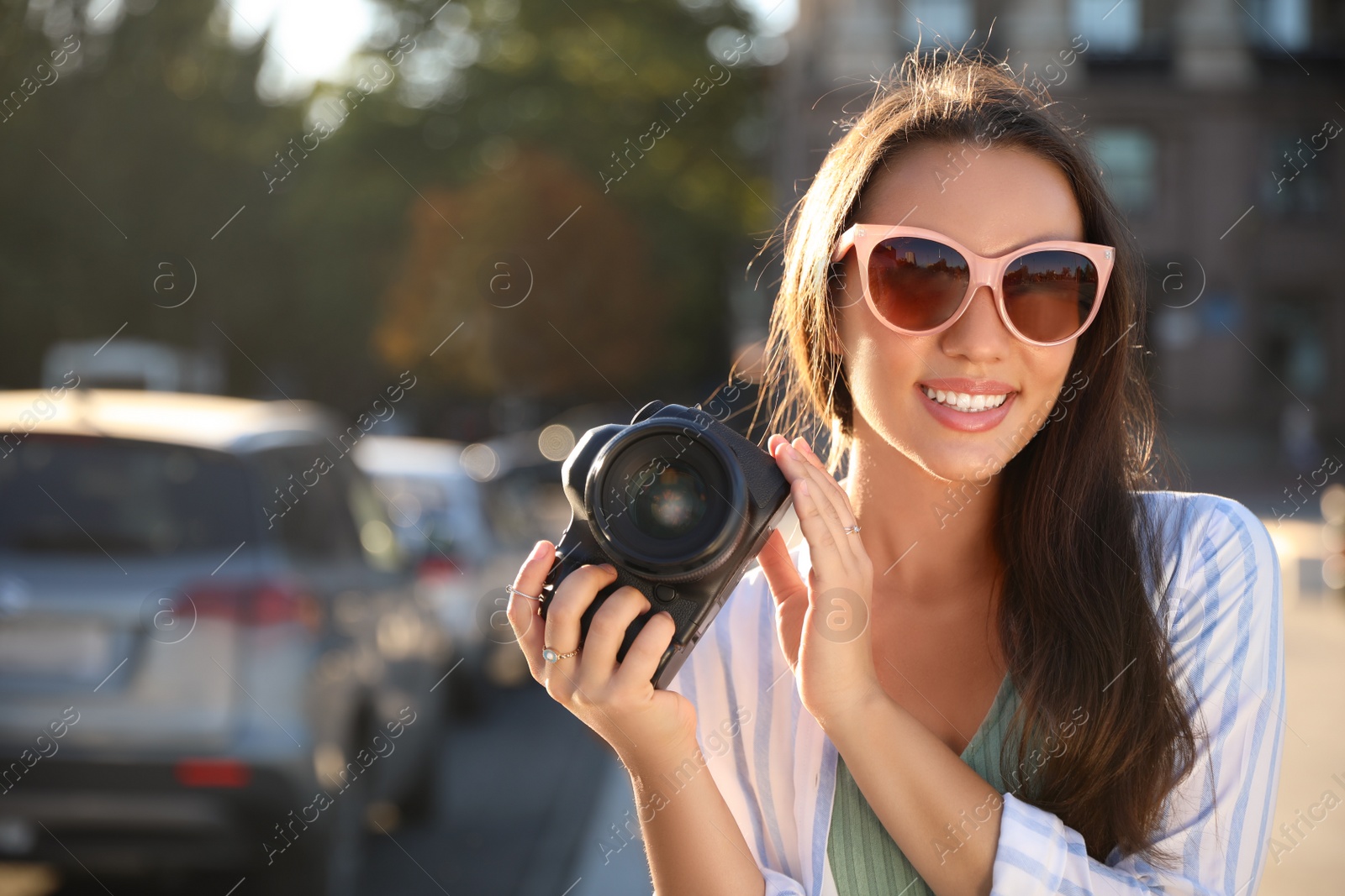 Photo of Young photographer with professional camera outdoors. Space for text