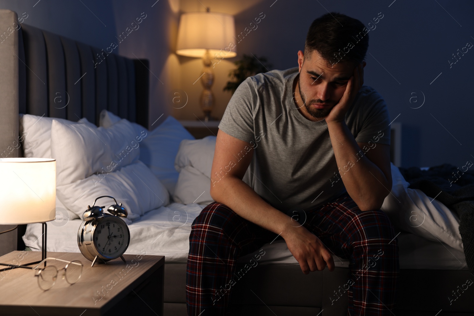 Photo of Frustrated man suffering from insomnia on bed