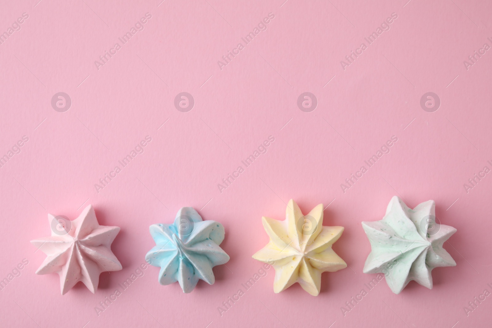 Photo of Many tasty meringue cookies on pink background, flat lay