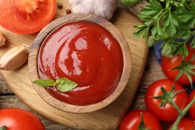 Photo of Tasty ketchup, fresh tomatoes, parsley and spices on wooden table, flat lay