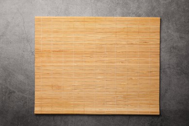 Photo of Bamboo mat on grey table, top view. Space for text