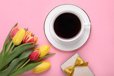 Photo of Cup of coffee, beautiful tulips and gift box on pink background, flat lay