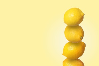 Stack of whole fresh lemons on pale goldenrod background, space for text
