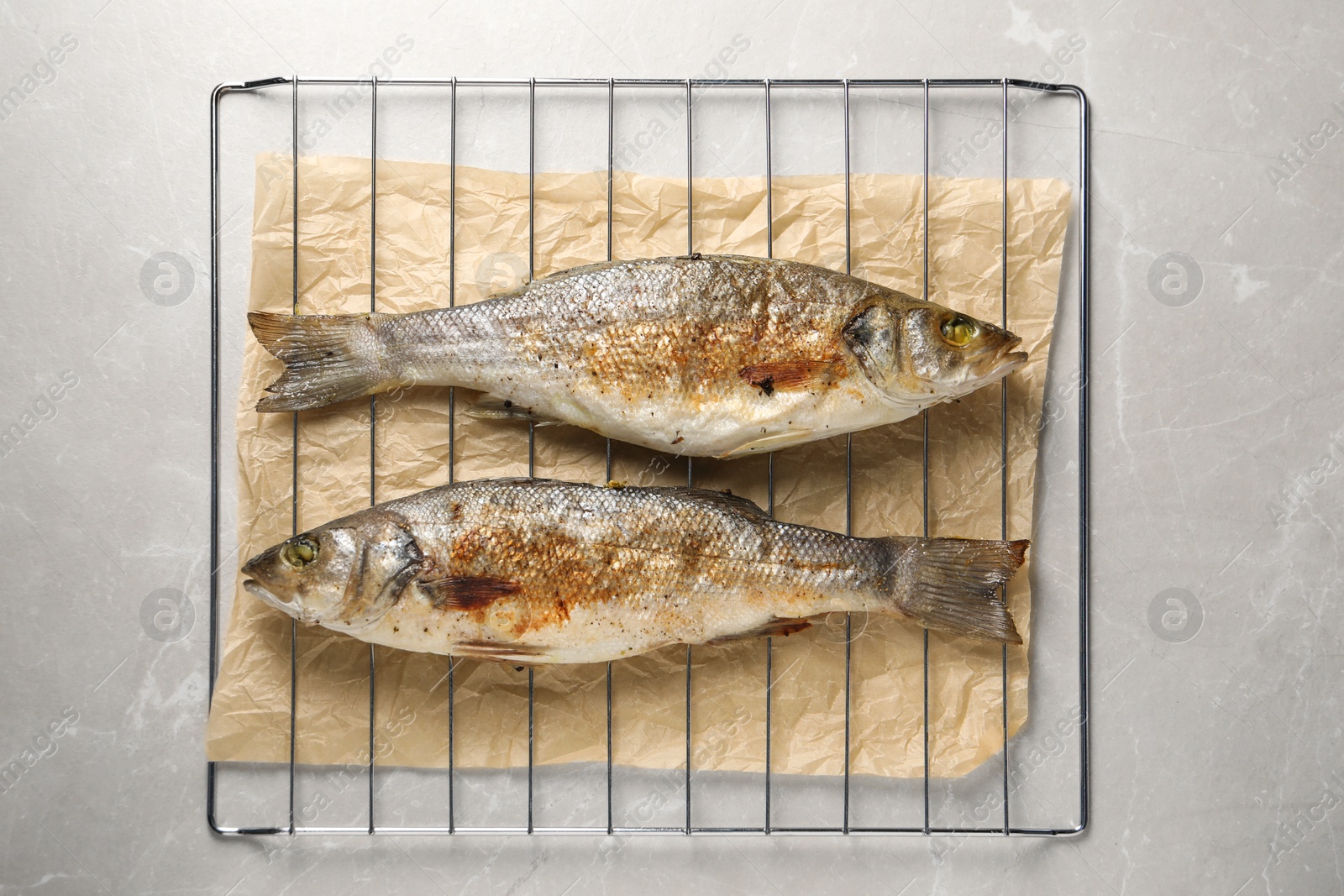 Photo of Baked fish on light marble table, top view