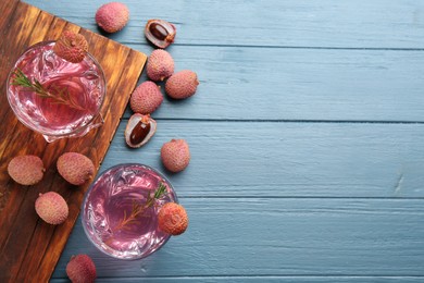 Photo of Delicious lychee cocktail and fresh fruits on light blue wooden table, flat lay. Space for text