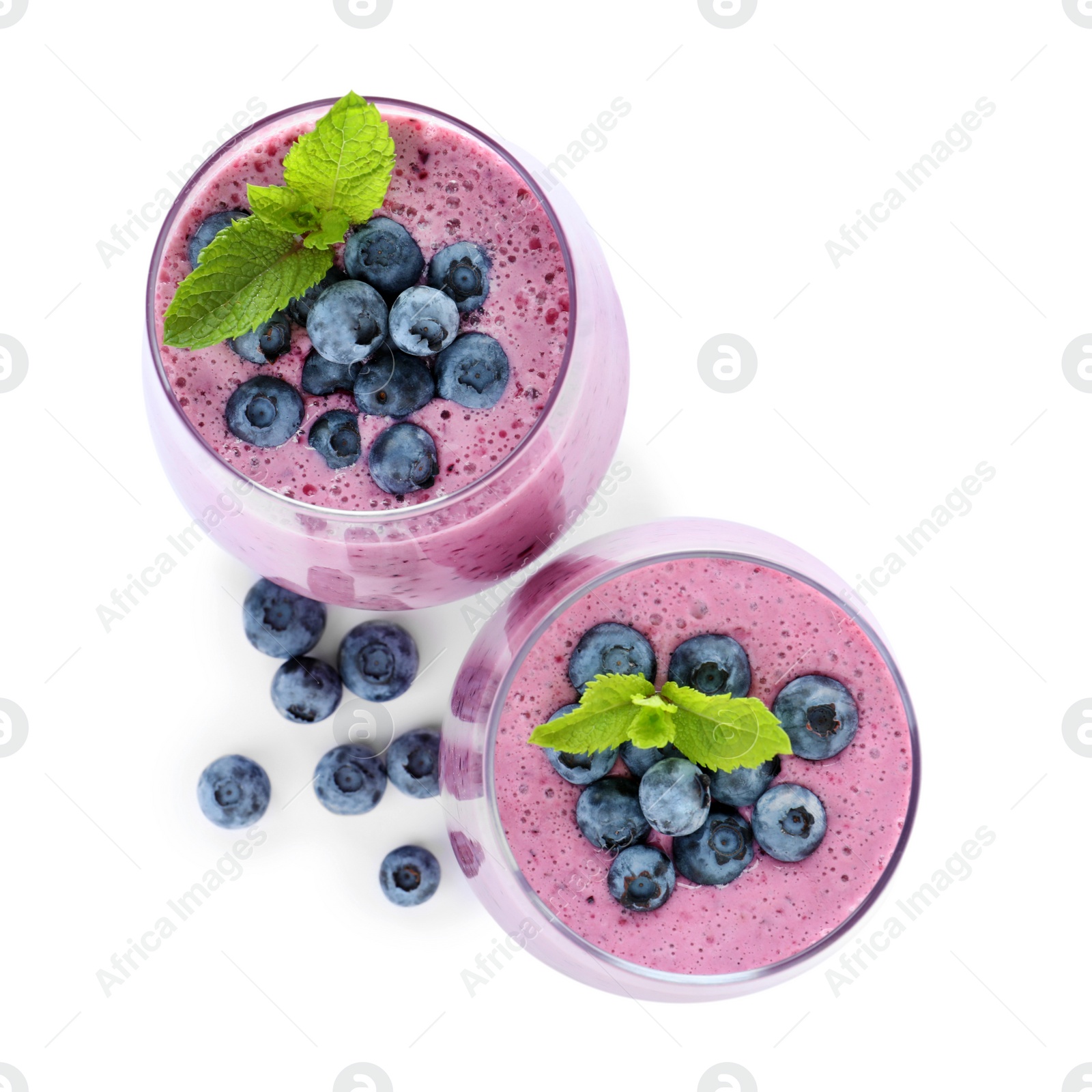 Photo of Glasses of tasty blueberry smoothie with mint on white background, top view