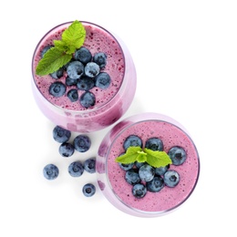 Photo of Glasses of tasty blueberry smoothie with mint on white background, top view