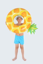 Cute little child in beachwear with bright inflatable ring on white background