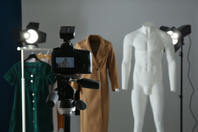 Photo of Ghost mannequins, clothes and professional lighting equipment in modern photo studio, focus on camera
