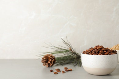 Bowl with pine nuts on table against light background. Space for text