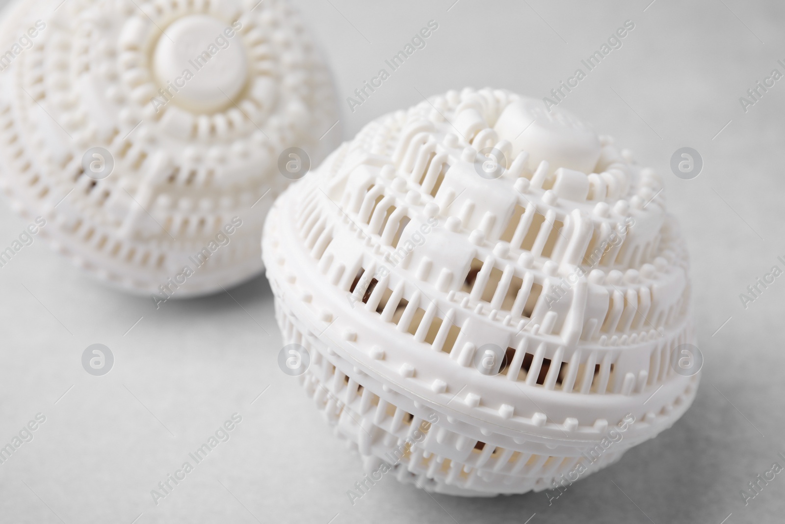 Photo of Dryer balls for washing machine on light grey table, closeup. Laundry detergent substitute