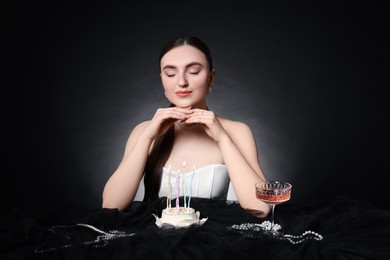 Photo of Fashionable photo of attractive young woman making wish with her Birthday cake on black background