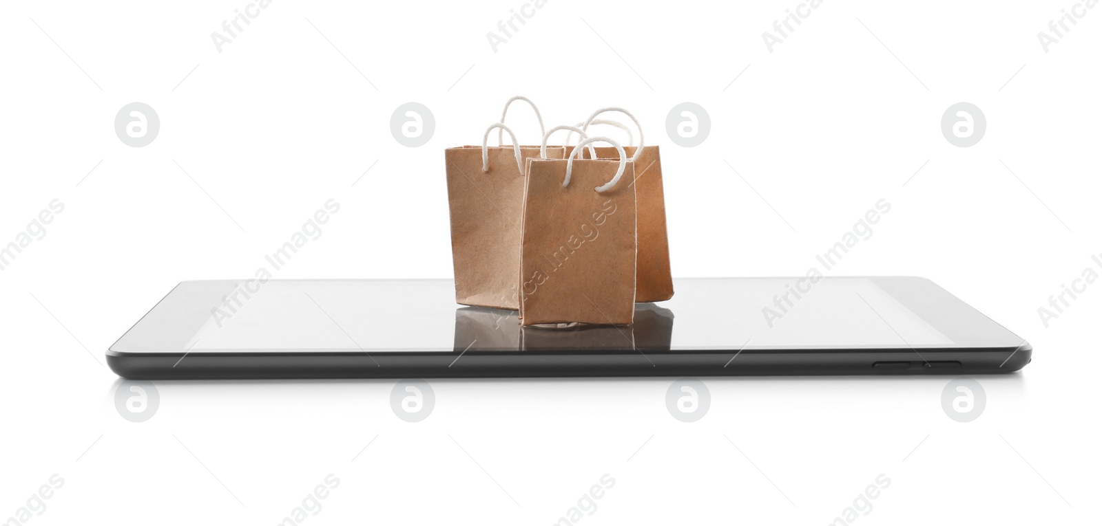 Photo of Internet shopping. Small paper bags and modern tablet on white background