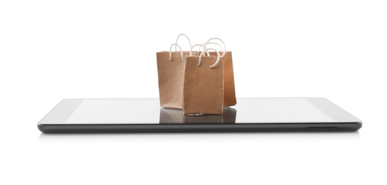Internet shopping. Small paper bags and modern tablet on white background