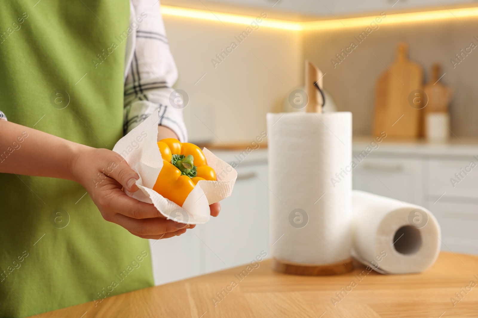 Photo of Woman wiping bell pepper with paper towel in kitchen, closeup. Space for text