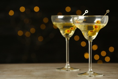 Glasses of Classic Dry Martini with olives on grey table against blurred background. Space for text