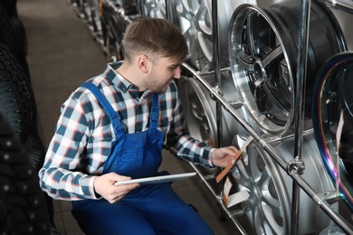 Photo of Young male mechanic with tablet computer in automobile service center