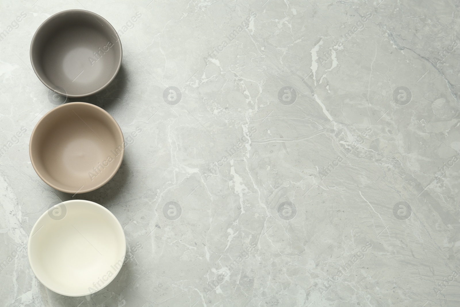 Photo of Stylish empty ceramic bowls on grey table, flat lay and space for text. Cooking utensils