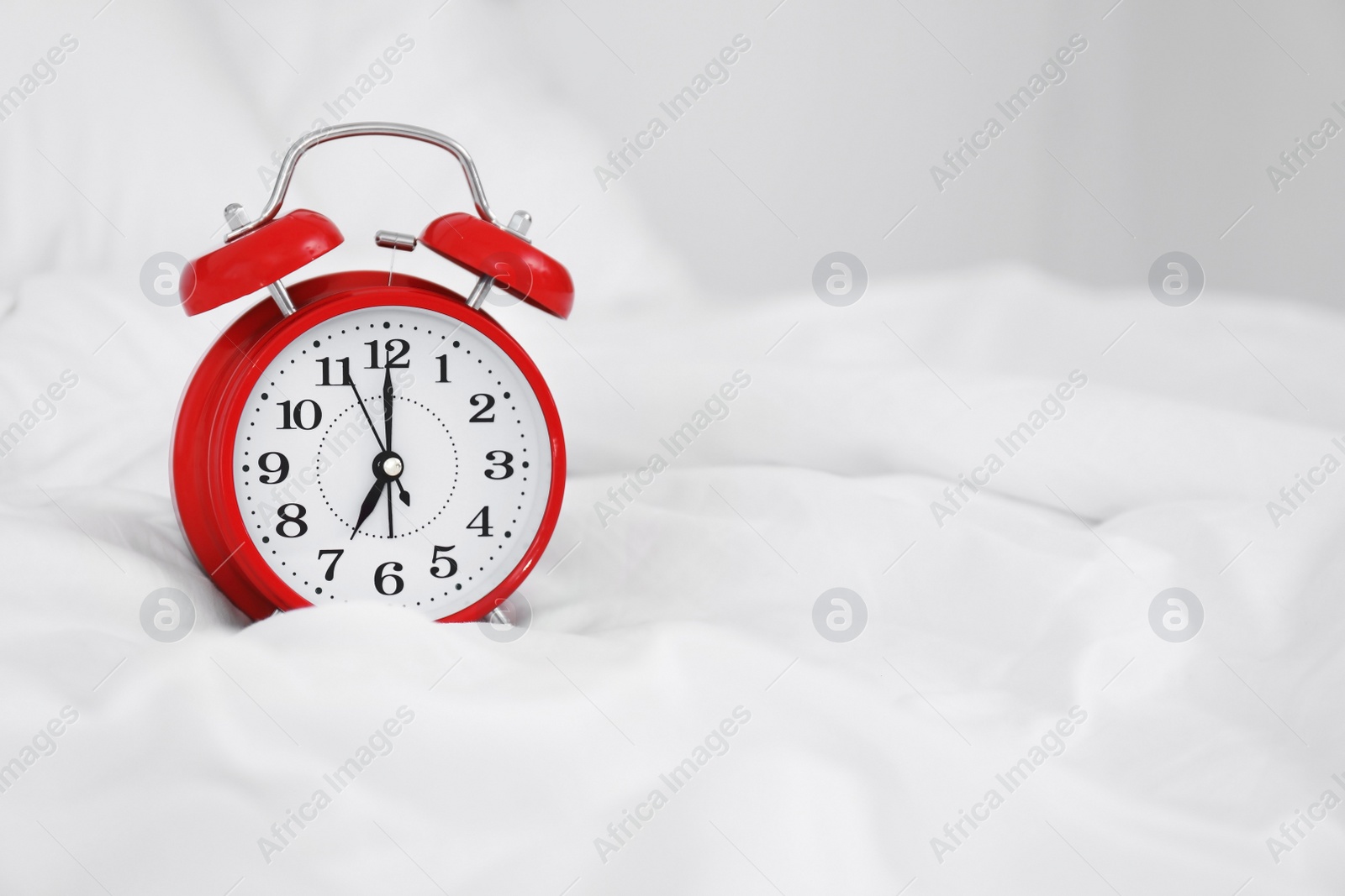 Photo of Analog alarm clock on bed. Time of day