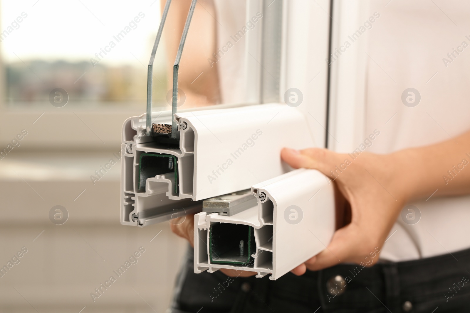 Photo of Woman holding sample of modern window profile on blurred background, closeup