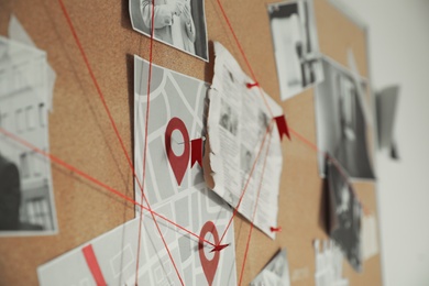 Photo of Detective board with crime scene photos and red threads, closeup