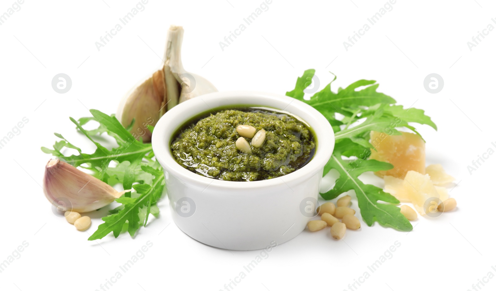 Photo of Bowl of tasty arugula pesto and ingredients on white background