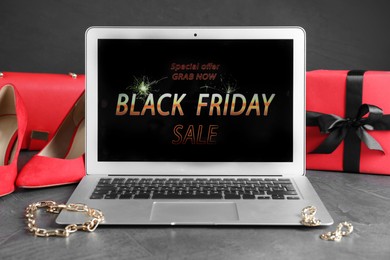 Photo of Laptop, gift box, shoes and jewelry on grey table. Black Friday sale