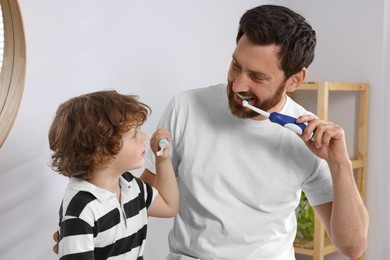 Photo of Father and his son brushing teeth together in bathroom