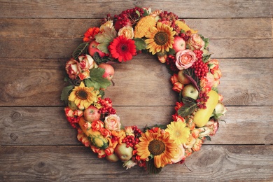 Photo of Beautiful autumnal wreath with flowers, berries and fruits on wooden background, top view. Space for text