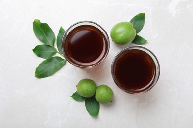 Photo of Delicious liqueur and green walnuts on light table, flat lay