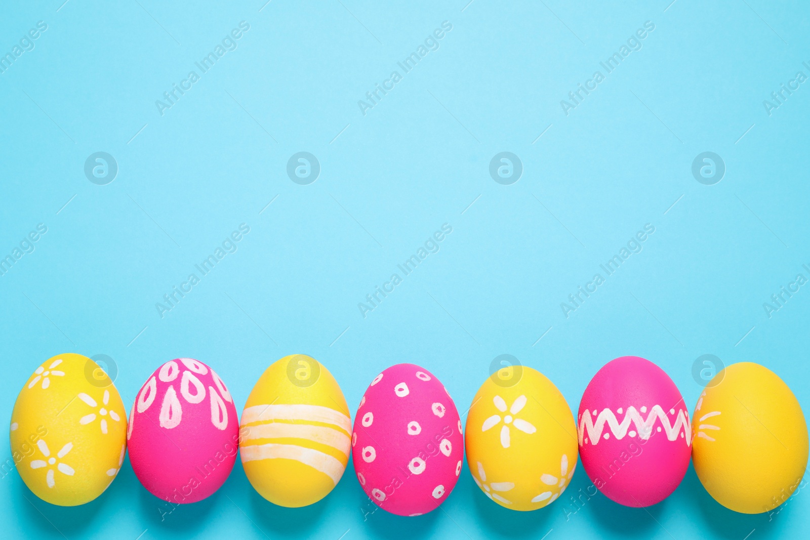 Photo of Colorful Easter eggs on light blue background, flat lay. Space for text