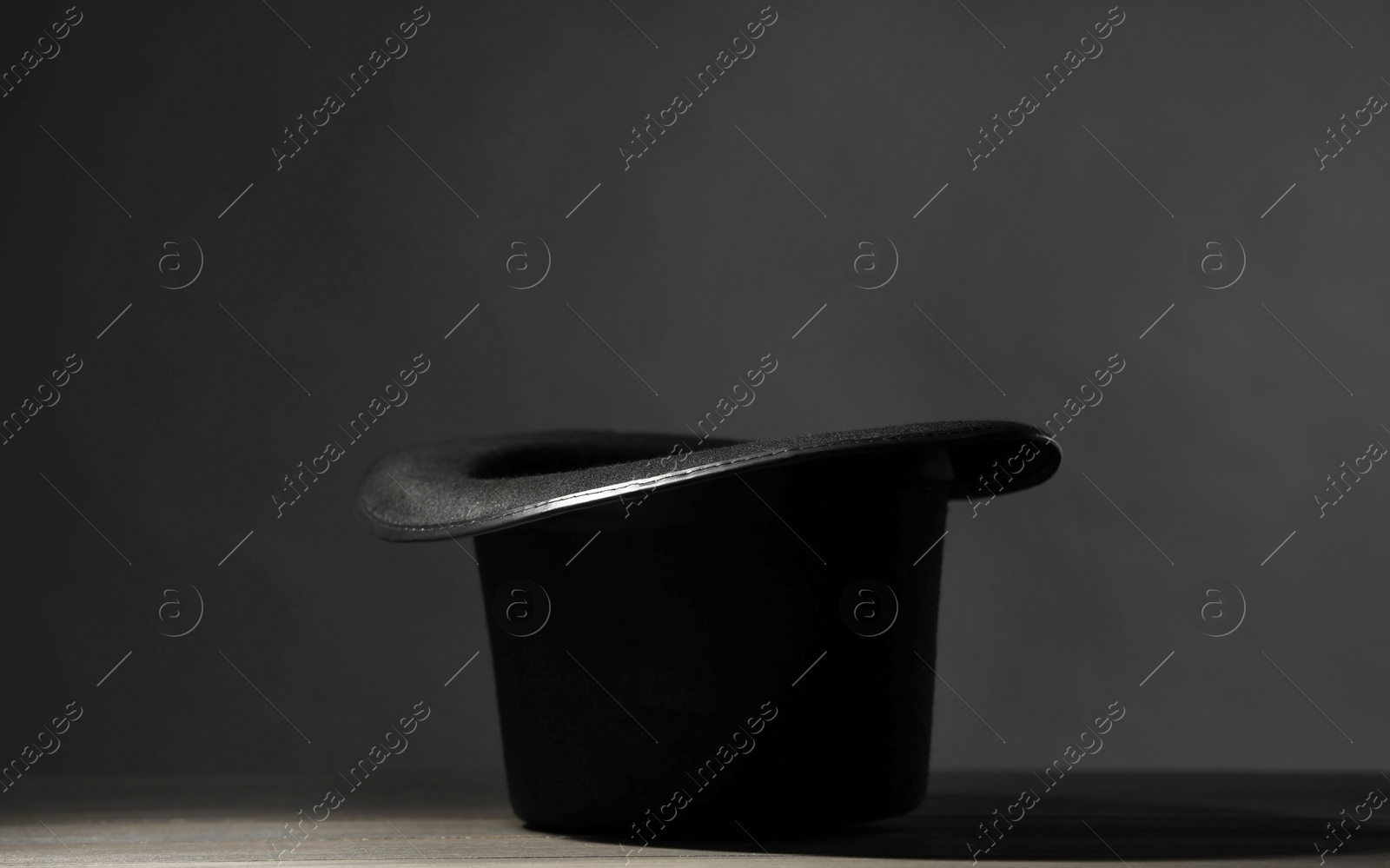 Photo of Magician's hat on white wooden table against black background