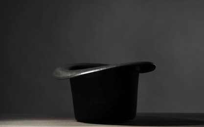 Magician's hat on white wooden table against black background