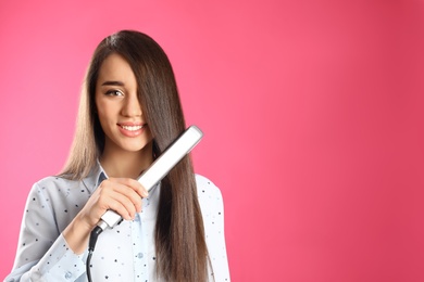 Happy woman using hair iron on color background. Space for text