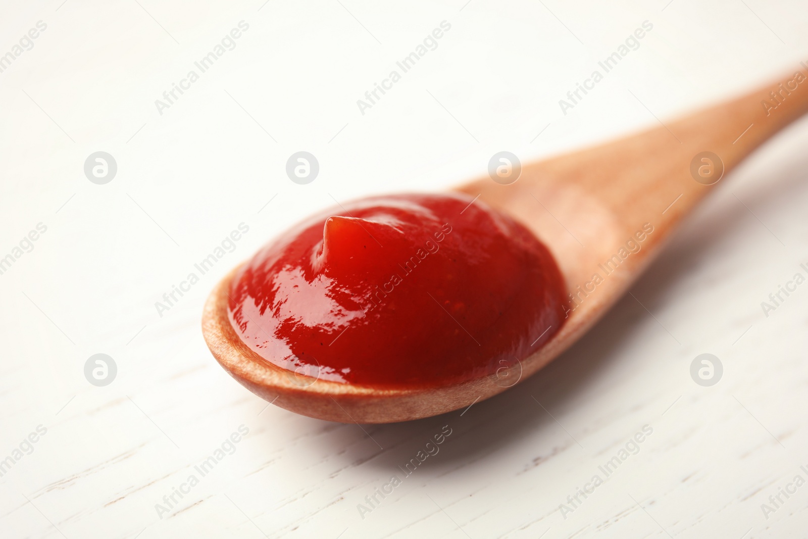 Photo of Homemade tomato sauce in spoon on wooden table