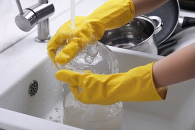 Woman washing glass pot in kitchen sink, closeup