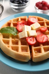 Tasty Belgian waffle with fresh berries, cheese and honey on table, closeup