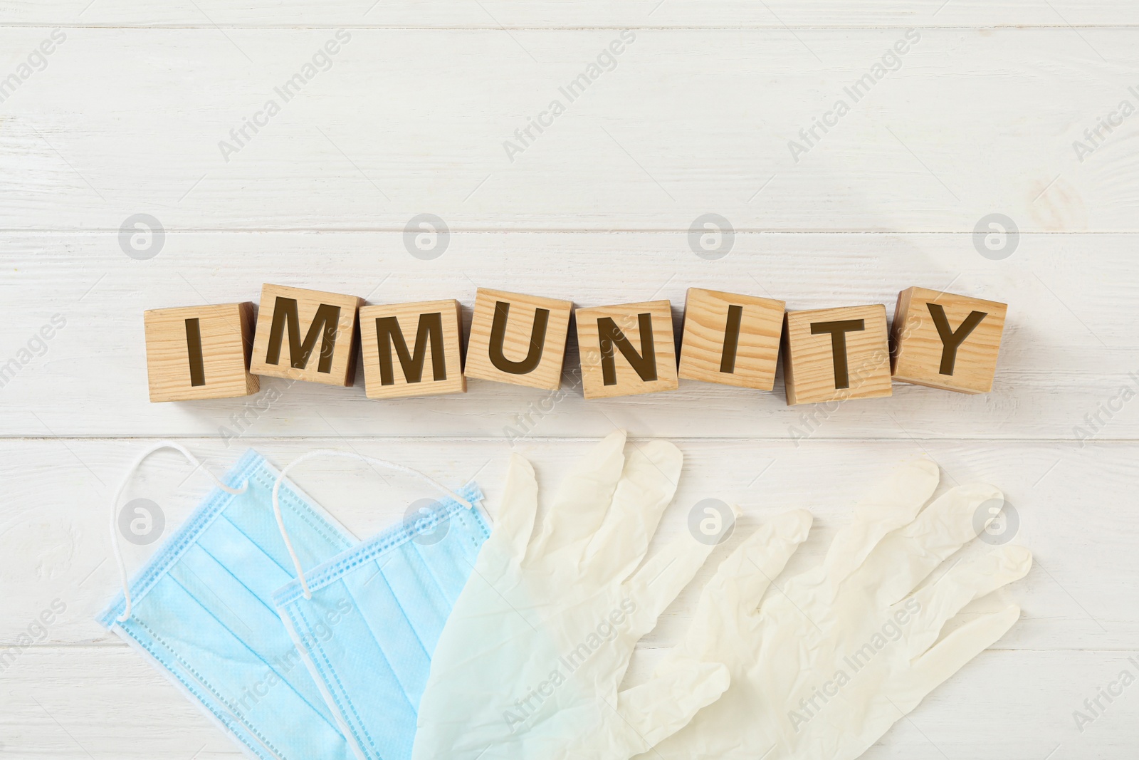 Photo of Cubes with word Immunity and medical items on white wooden table, flat lay