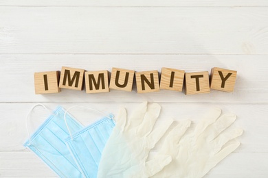 Photo of Cubes with word Immunity and medical items on white wooden table, flat lay