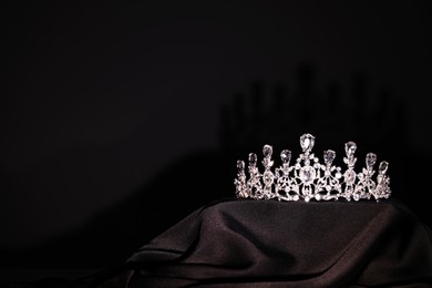 Beautiful silver tiara with diamonds on black cloth. Space for text