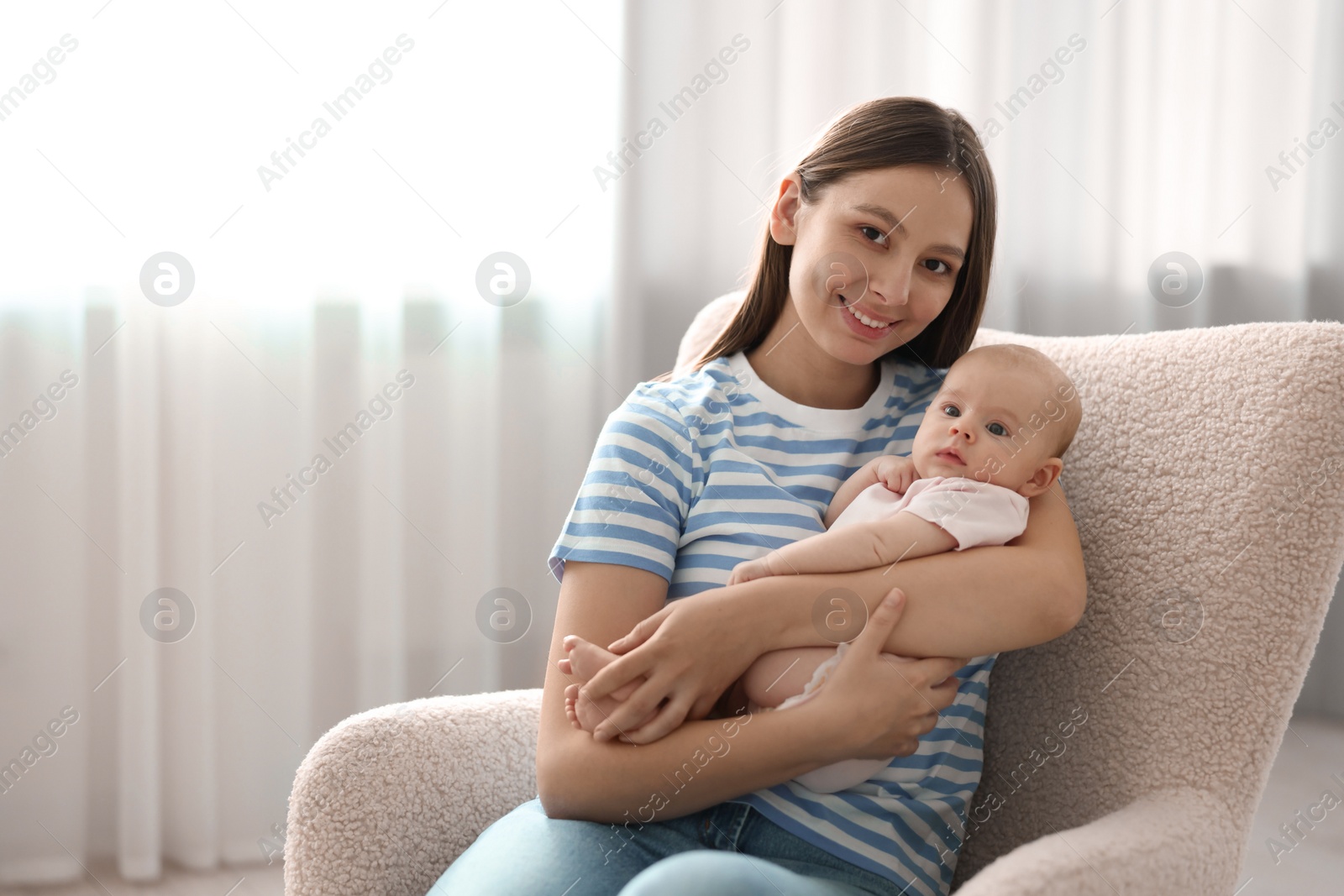 Photo of Mother with her cute baby in armchair at home, space for text
