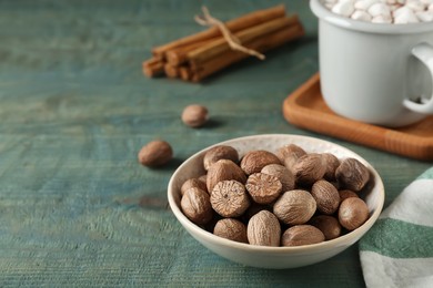 Photo of Nutmegs in bowl on blue wooden table. Space for text
